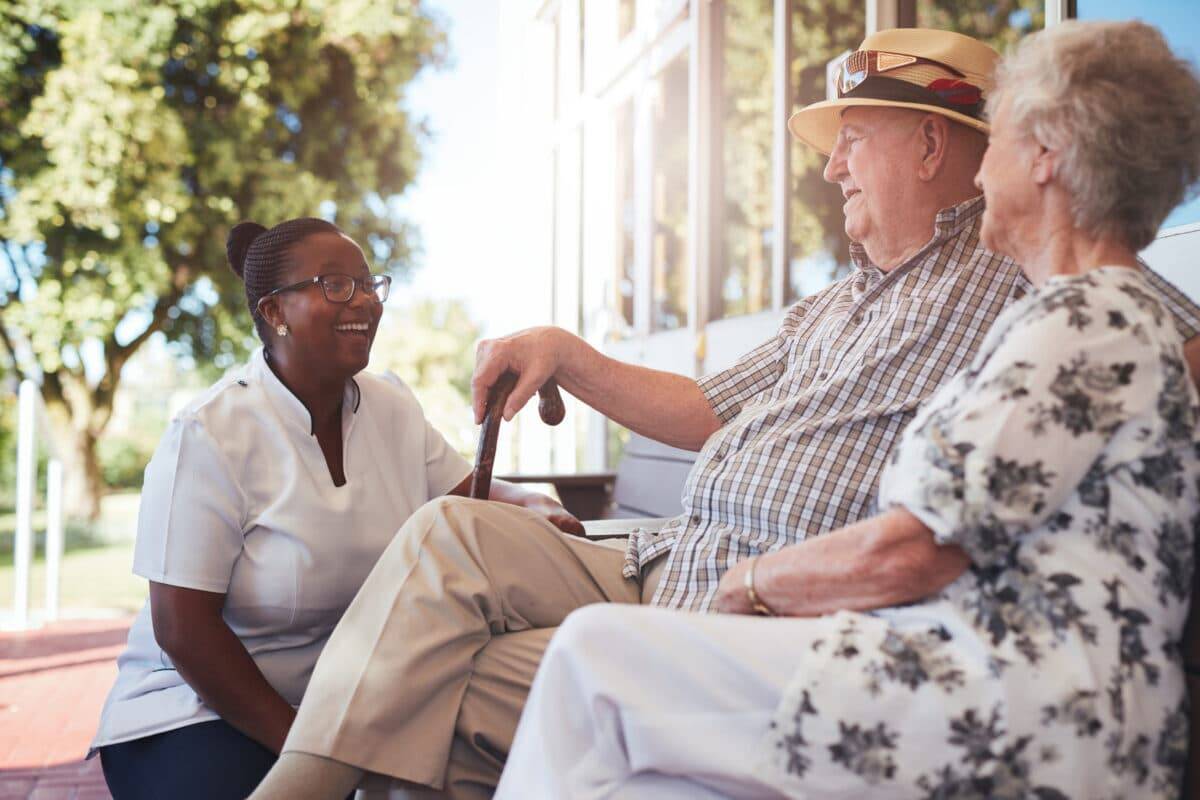 A Woman And Two Elderly People Sitting On A Bench.