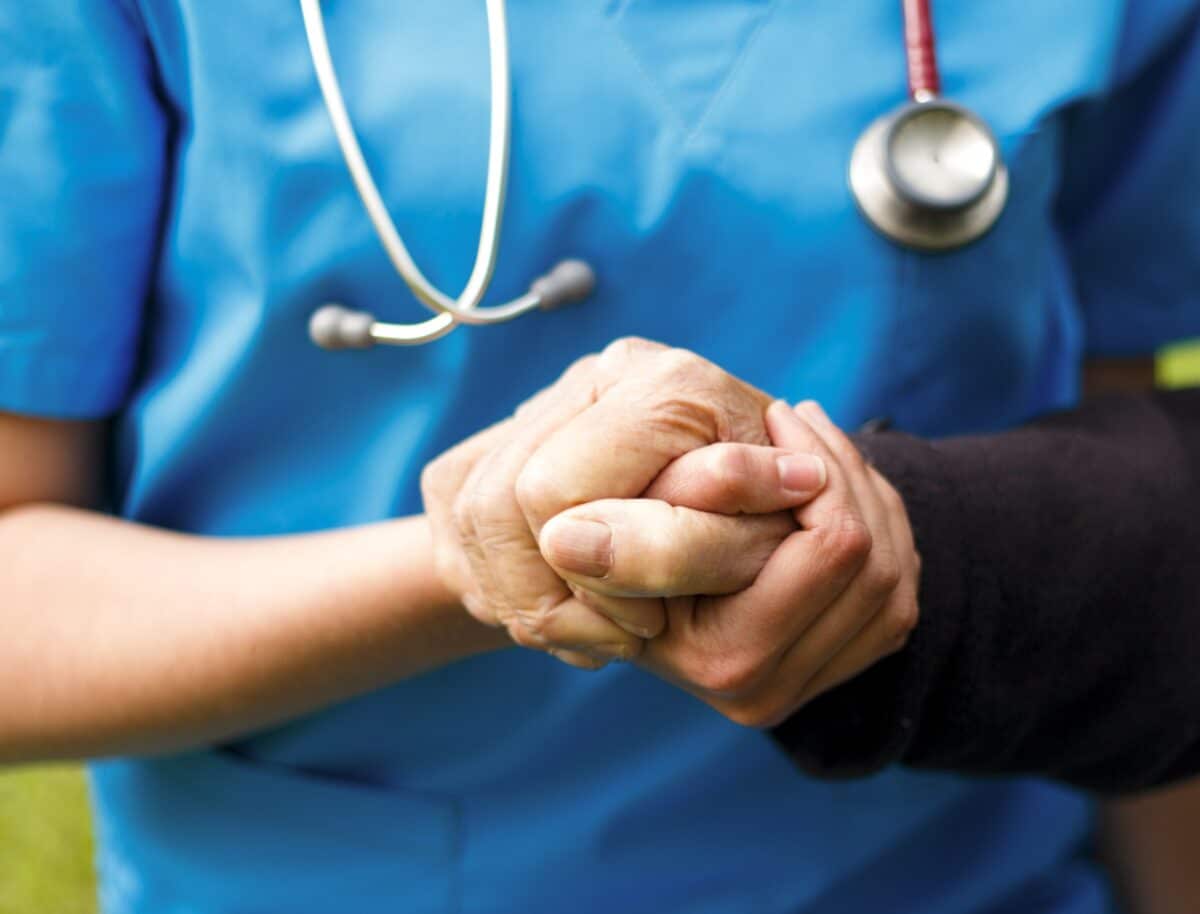 A Nurse Holding The Hand Of A Patient.